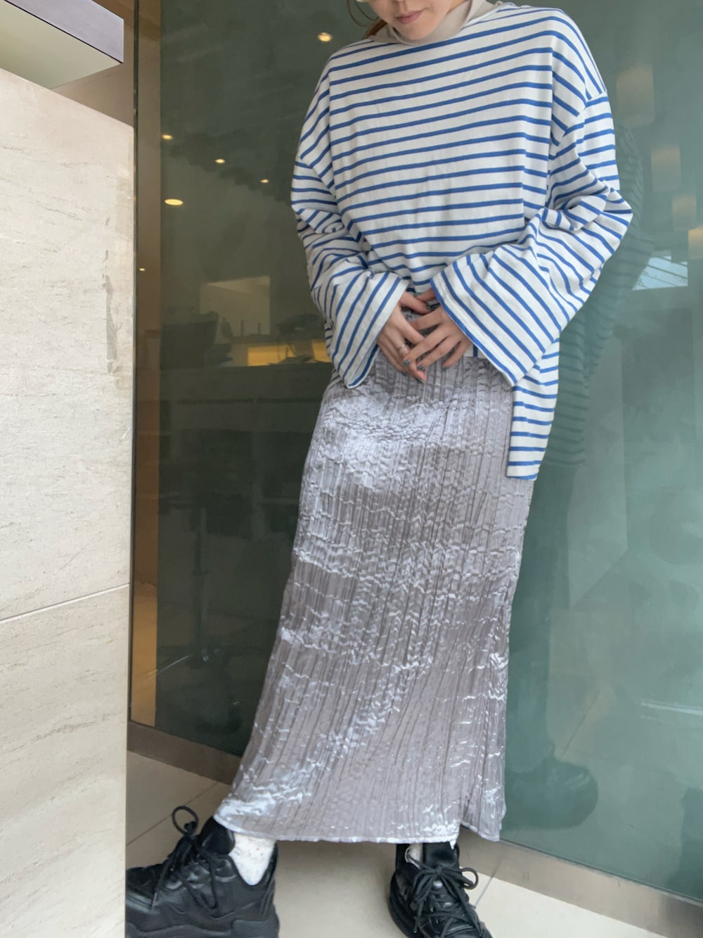 シルバー系のスカート、ブルー系のTシャツ/カットソー、ブラック系のスニーカーを着用したレディースの冬コーディネートの2枚目の写真