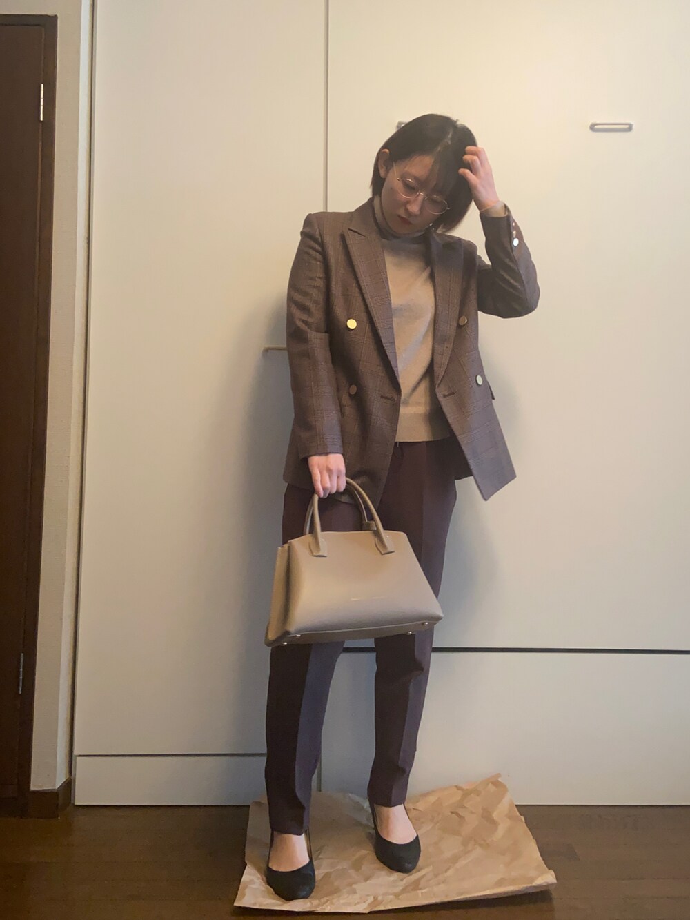 ベージュ系のハンドバッグ、ベージュ系のニット/セーター、ブラウン系のパンツを着用したレディースの冬コーディネートの3枚目の写真