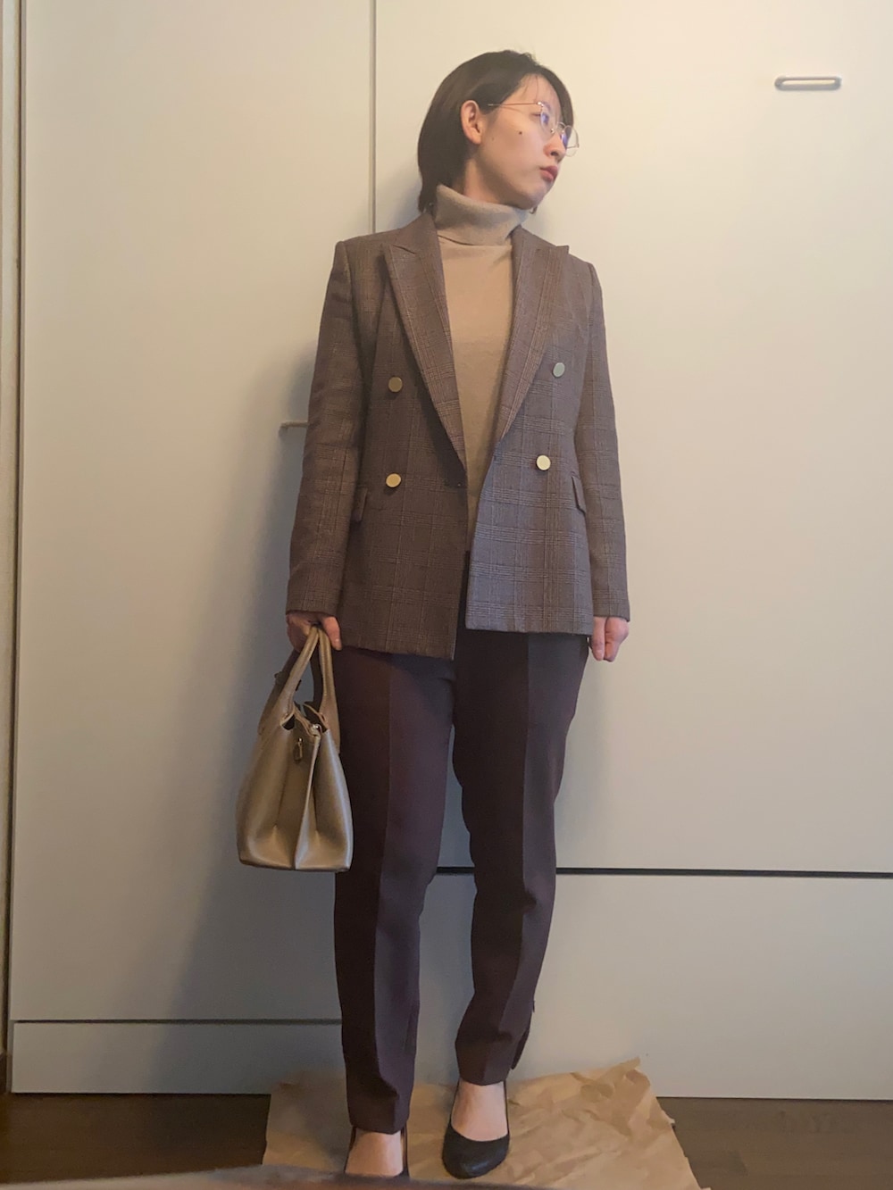 ベージュ系のハンドバッグ、ベージュ系のニット/セーター、ブラウン系のパンツを着用したレディースの冬コーディネートの2枚目の写真