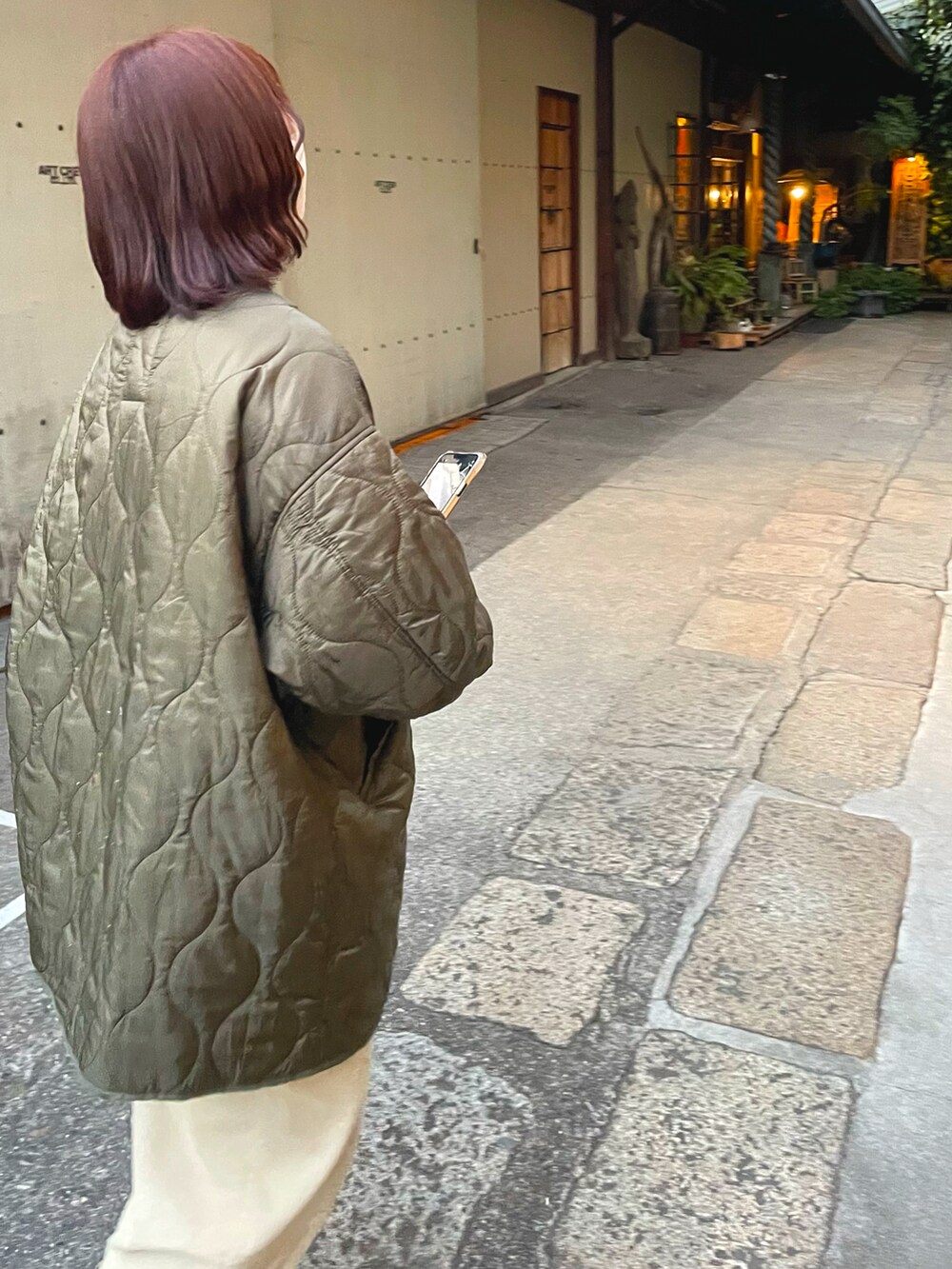 グリーン系のモッズコート、ベージュ系のパンツ、ブラウン系のブーツを着用したレディースの春コーディネートの2枚目の写真