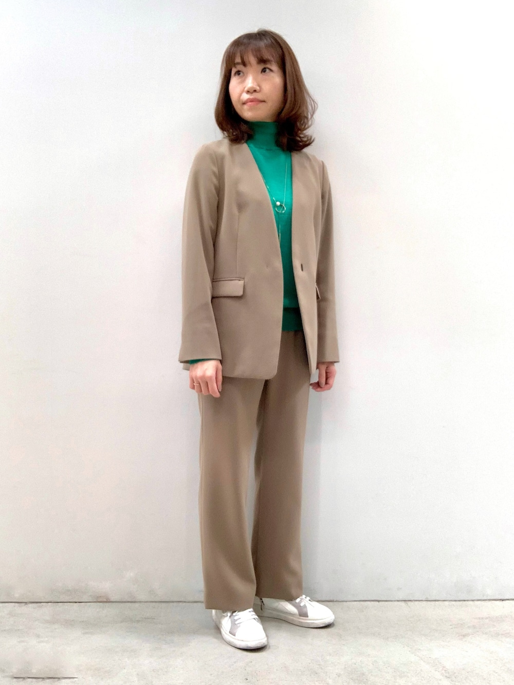 ベージュ系のスーツジャケット、ベージュ系のその他パンツ、グリーン系のニット/セーターを着用したレディースの秋コーディネートの3枚目の写真