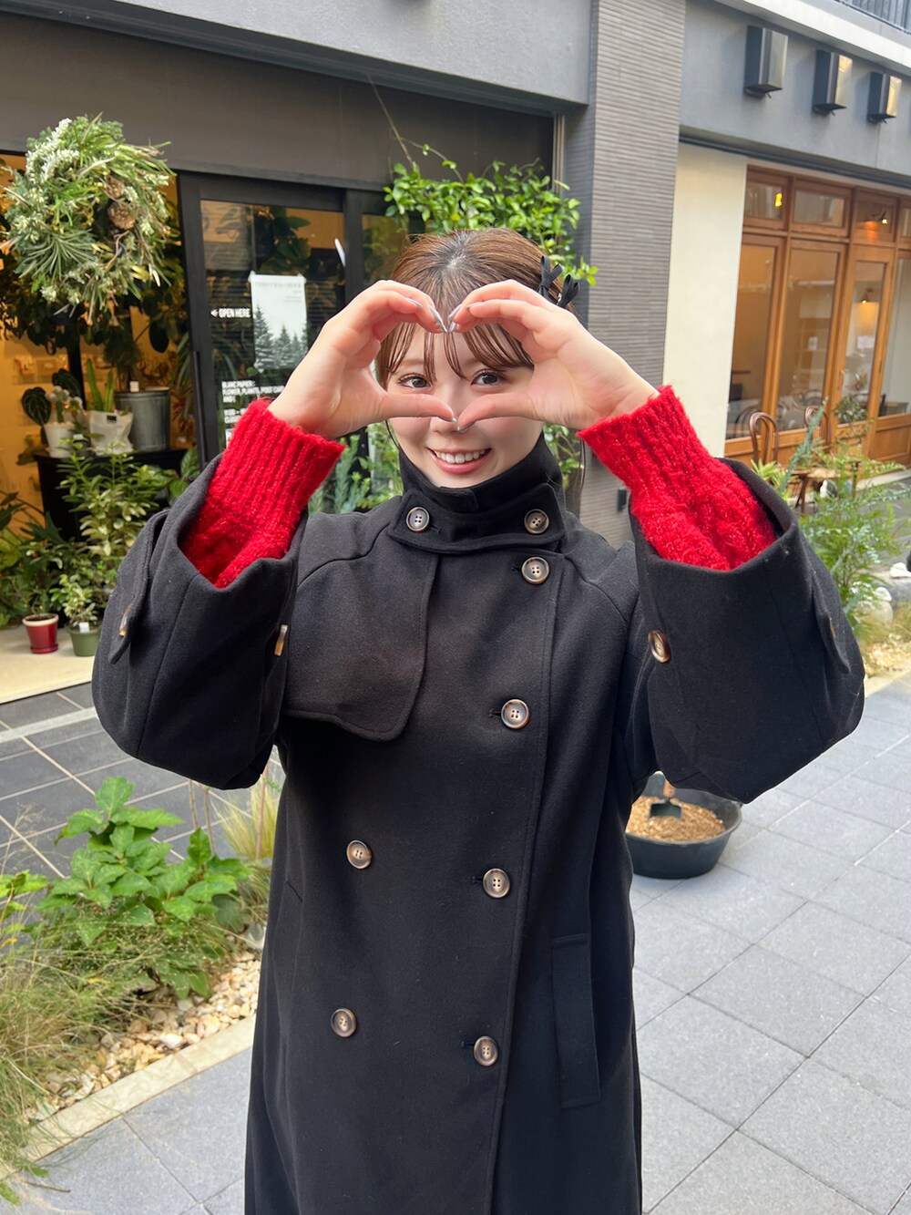 レッド系のトートバッグ、ブラック系のステンカラーコートを着用したレディースの秋コーディネートの3枚目の写真