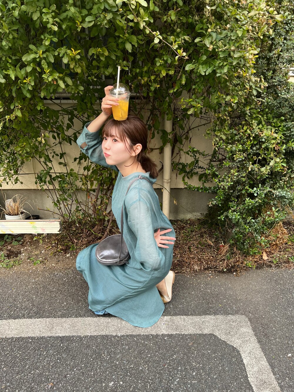 グリーン系のワンピース、グレー系のショルダーバッグ、イエロー系のパンプスを着用したレディースの春コーディネートの3枚目の写真