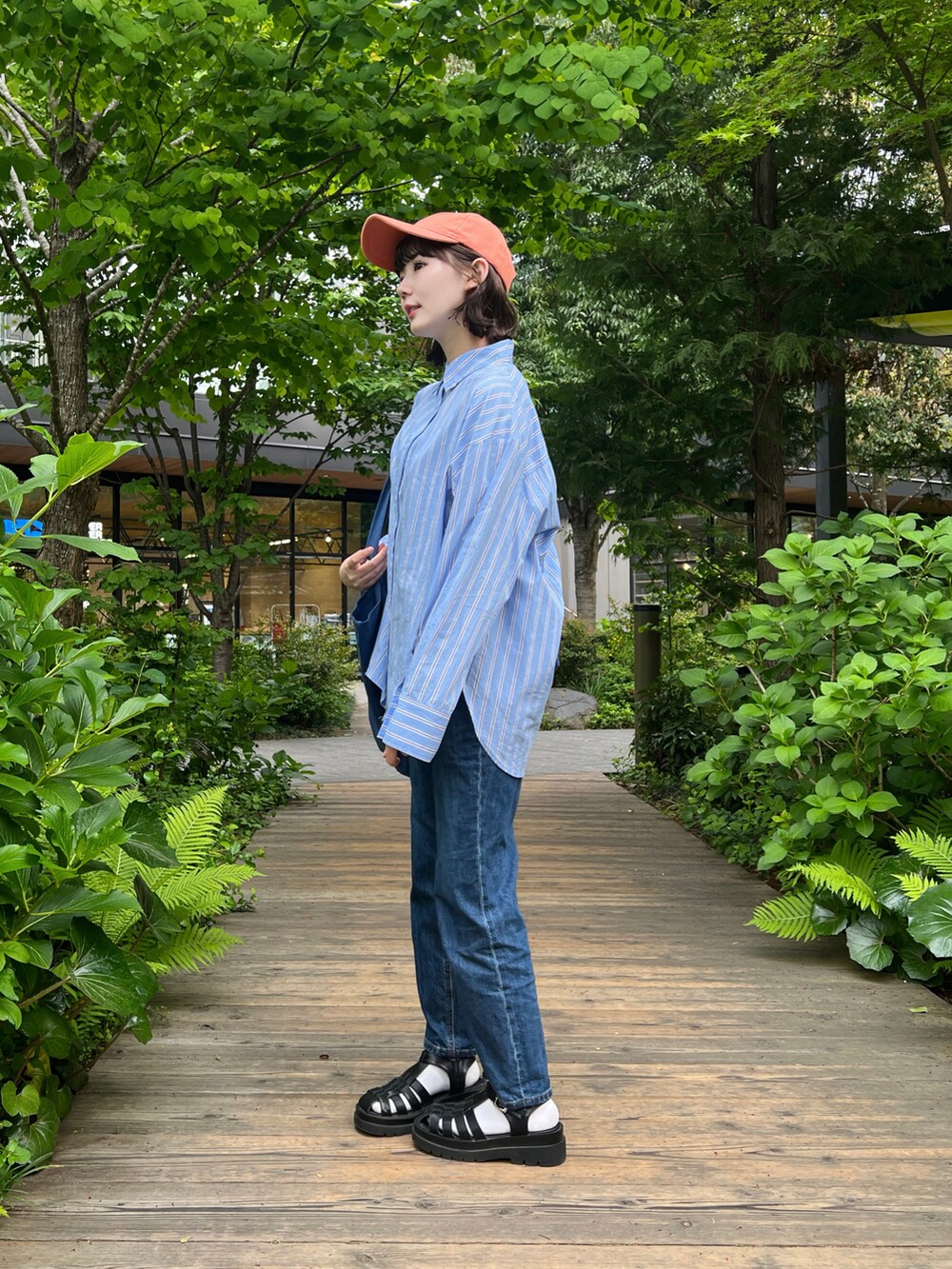ブルー系のシャツ/ブラウス、ブラック系のサンダル、ブルー系のデニムパンツを着用したレディースの春コーディネートの3枚目の写真