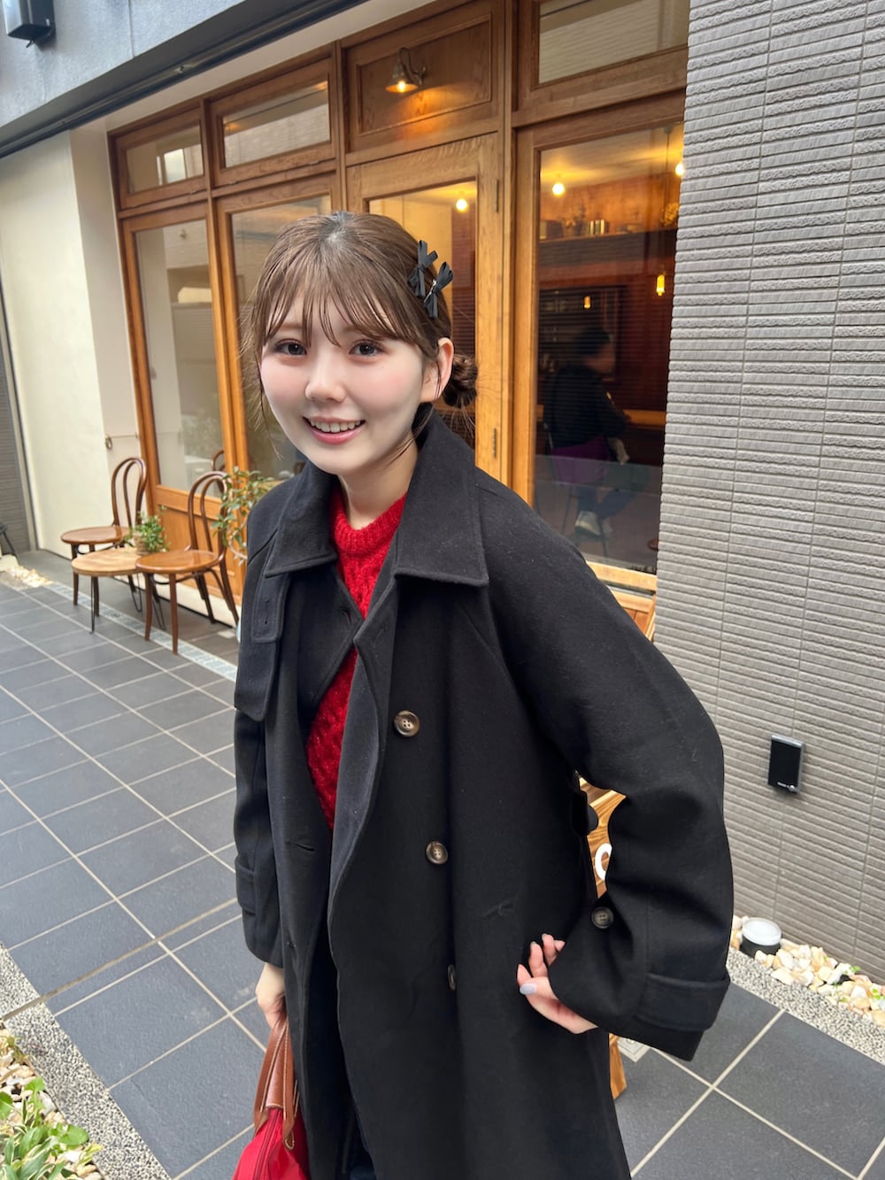 レッド系のトートバッグ、ブラック系のステンカラーコートを着用したレディースの秋コーディネートの2枚目の写真