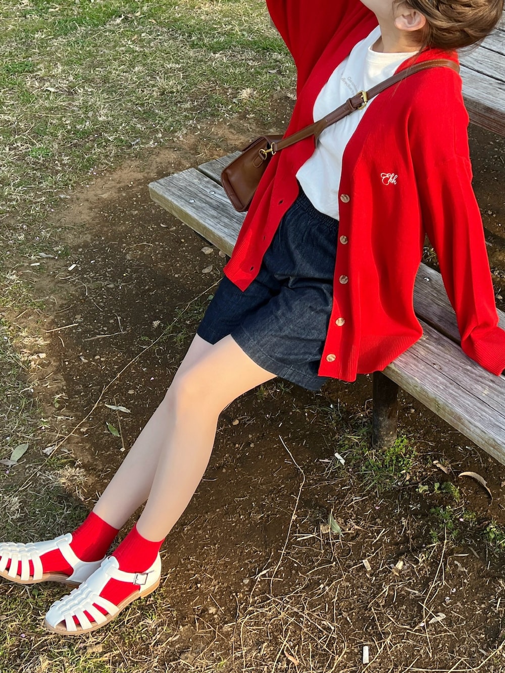 レッド系のカーディガン/ボレロ、ホワイト系のサンダルを着用したレディースの春コーディネートの2枚目の写真
