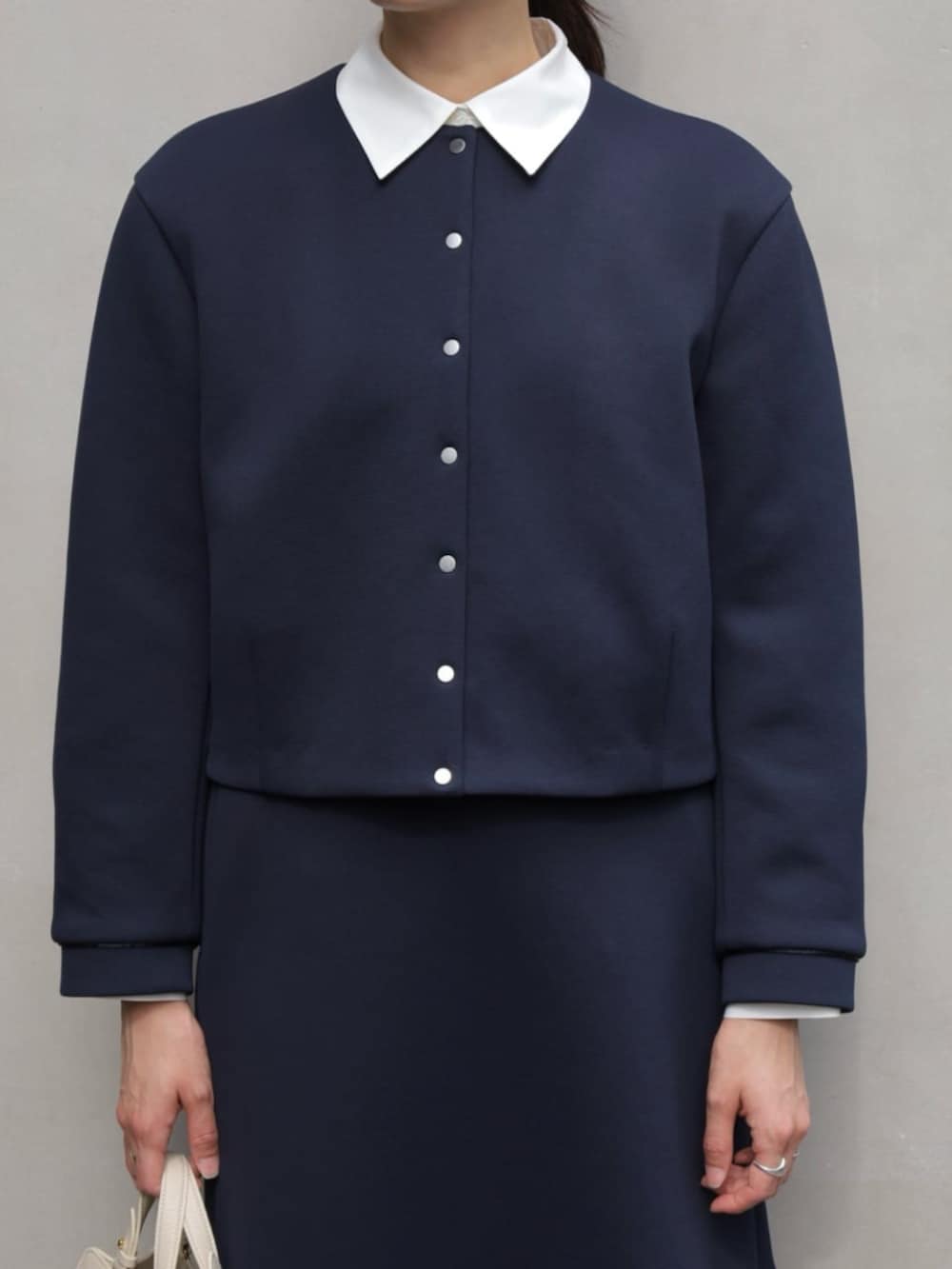 グレー系のパンプス、ブルー系のノーカラージャケット、ブルー系のスカートを着用したレディースの秋コーディネートの2枚目の写真