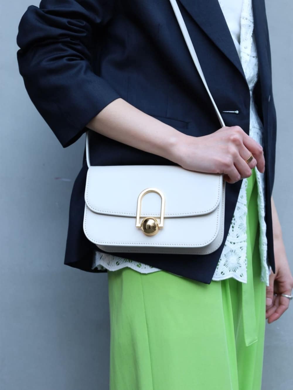 ベージュ系のショルダーバッグ、ブルー系のテーラードジャケット、ホワイト系のテーラードジャケットを着用したレディースの春コーディネートの4枚目の写真