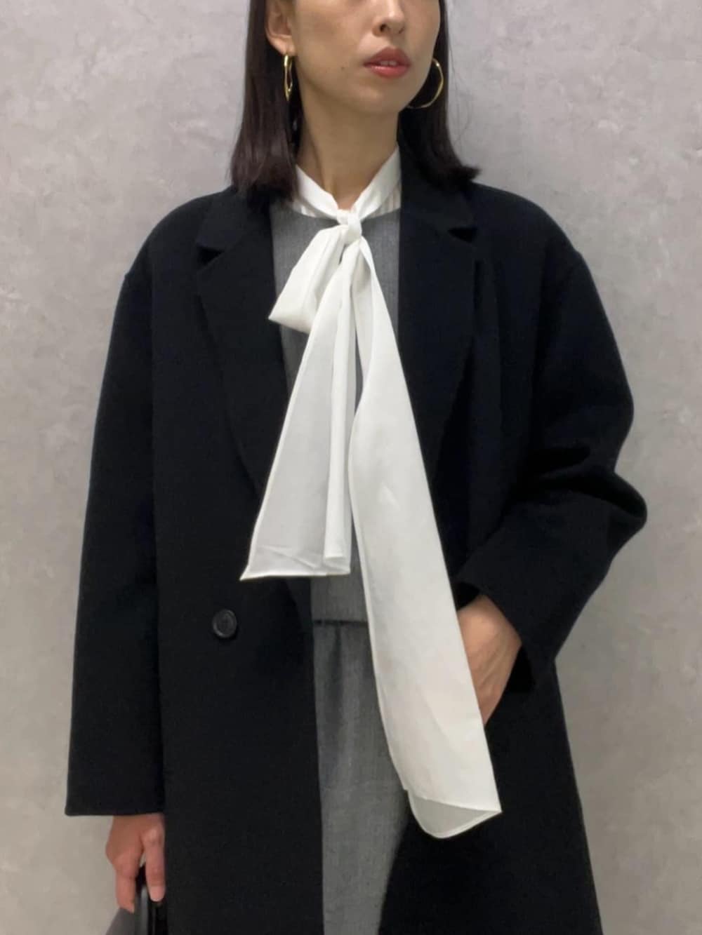 ブラック系のパンプス、ブラック系のチェスターコート、ホワイト系のシャツ/ブラウスを着用したレディースの冬コーディネートの2枚目の写真
