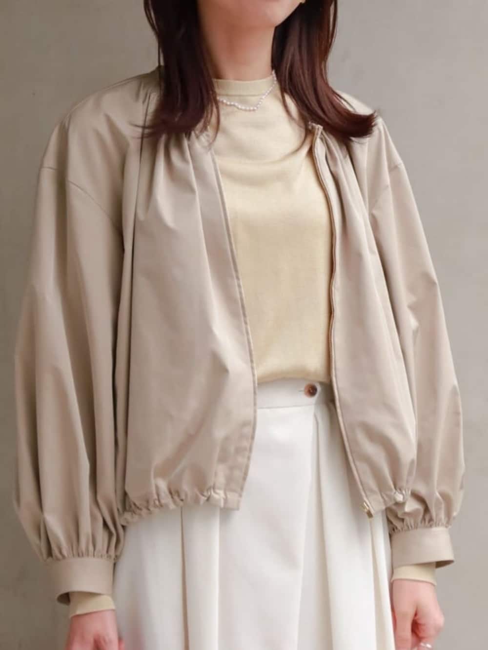 ベージュ系のブルゾン、ベージュ系のニット/セーター、パープル系のネックレスを着用したレディースの冬コーディネートの2枚目の写真