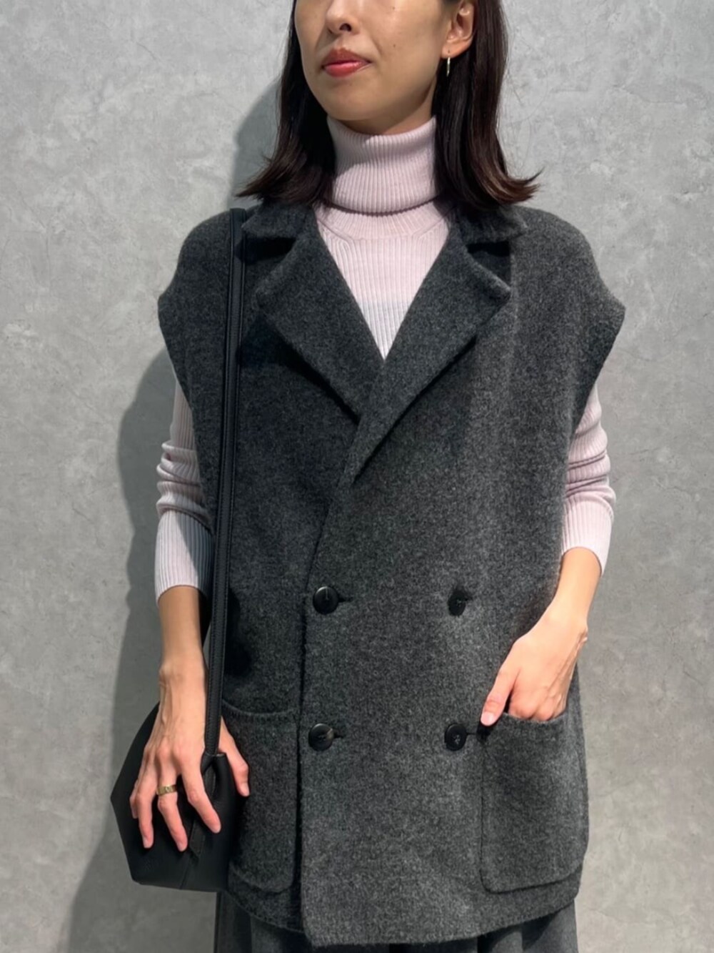 グレー系のベスト、ピンク系のニット/セーター、グレー系のスカートを着用したレディースの秋コーディネートの2枚目の写真