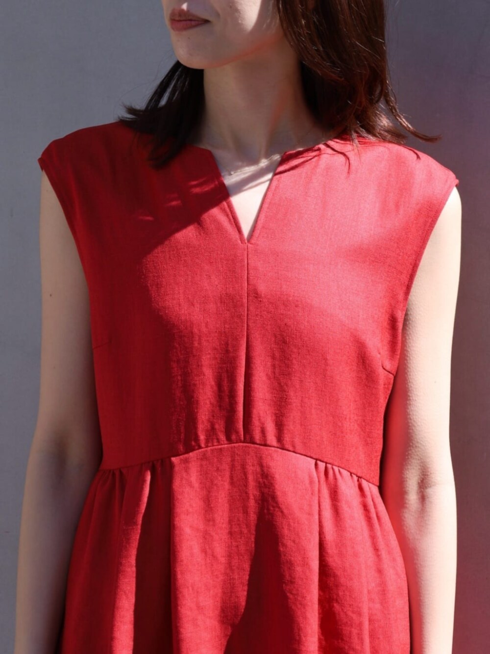 イエロー系のサンダル、レッド系のワンピース、ブラウン系のハンドバッグを着用したレディースの夏コーディネートの2枚目の写真