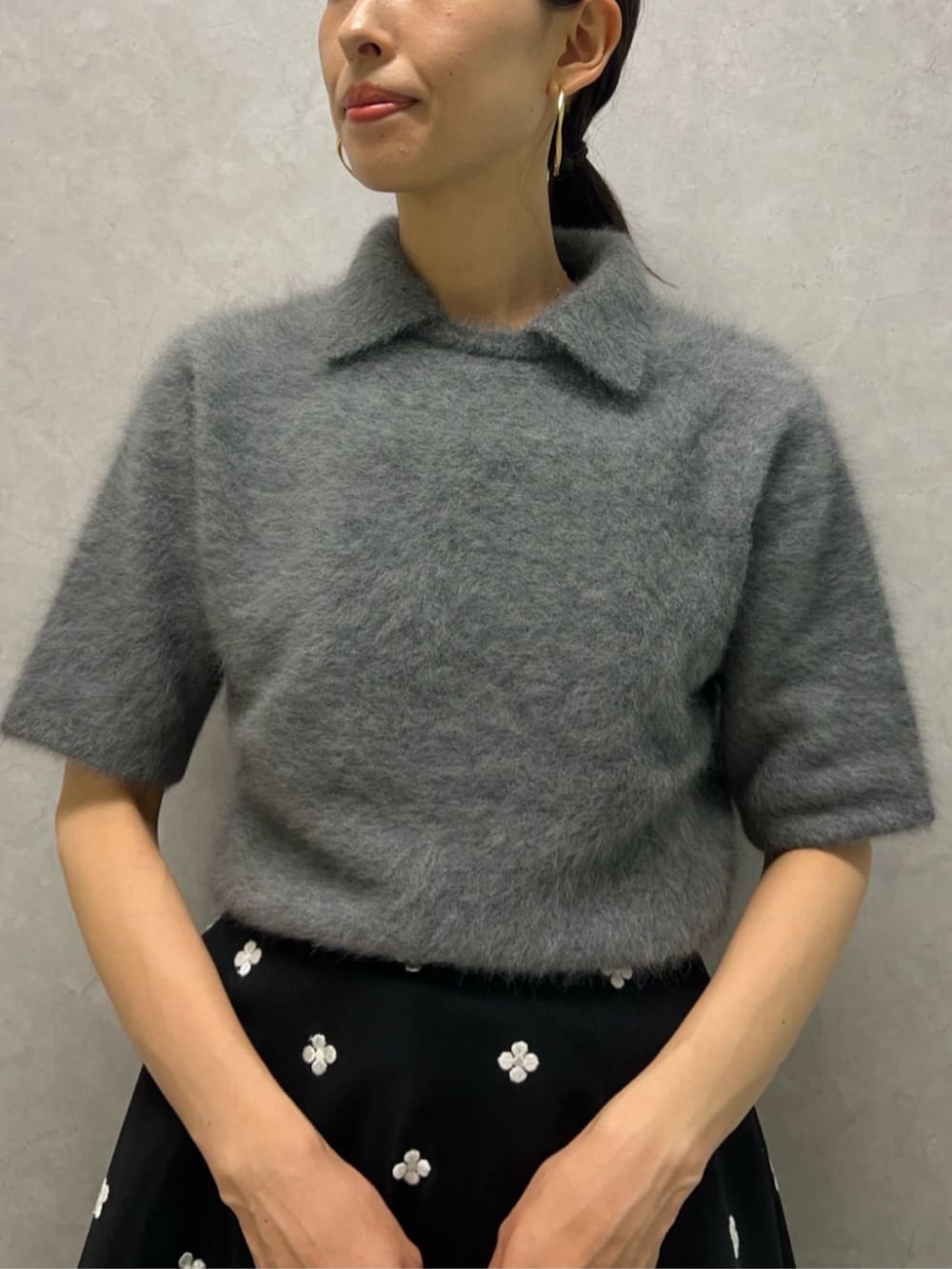 グレー系のニット/セーター、ブラック系のスカート、ブラック系のハンドバッグを着用したレディースの秋コーディネートの2枚目の写真