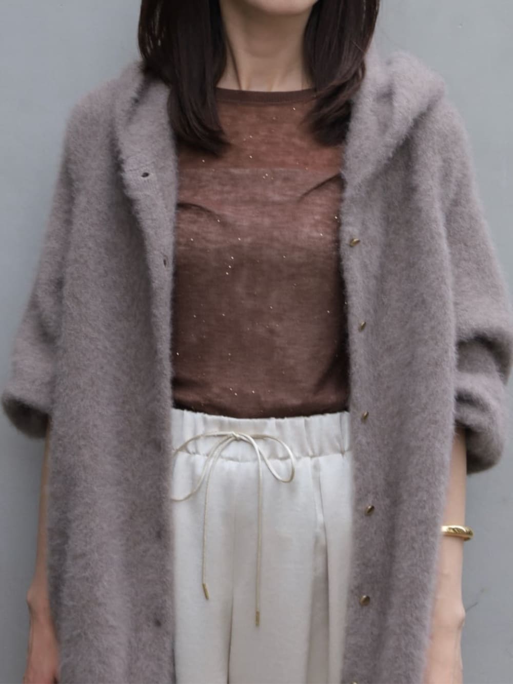 ベージュ系のその他アウター、グレー系のニット/セーター、ホワイト系のクラッチバッグを着用したレディースの秋コーディネートの2枚目の写真