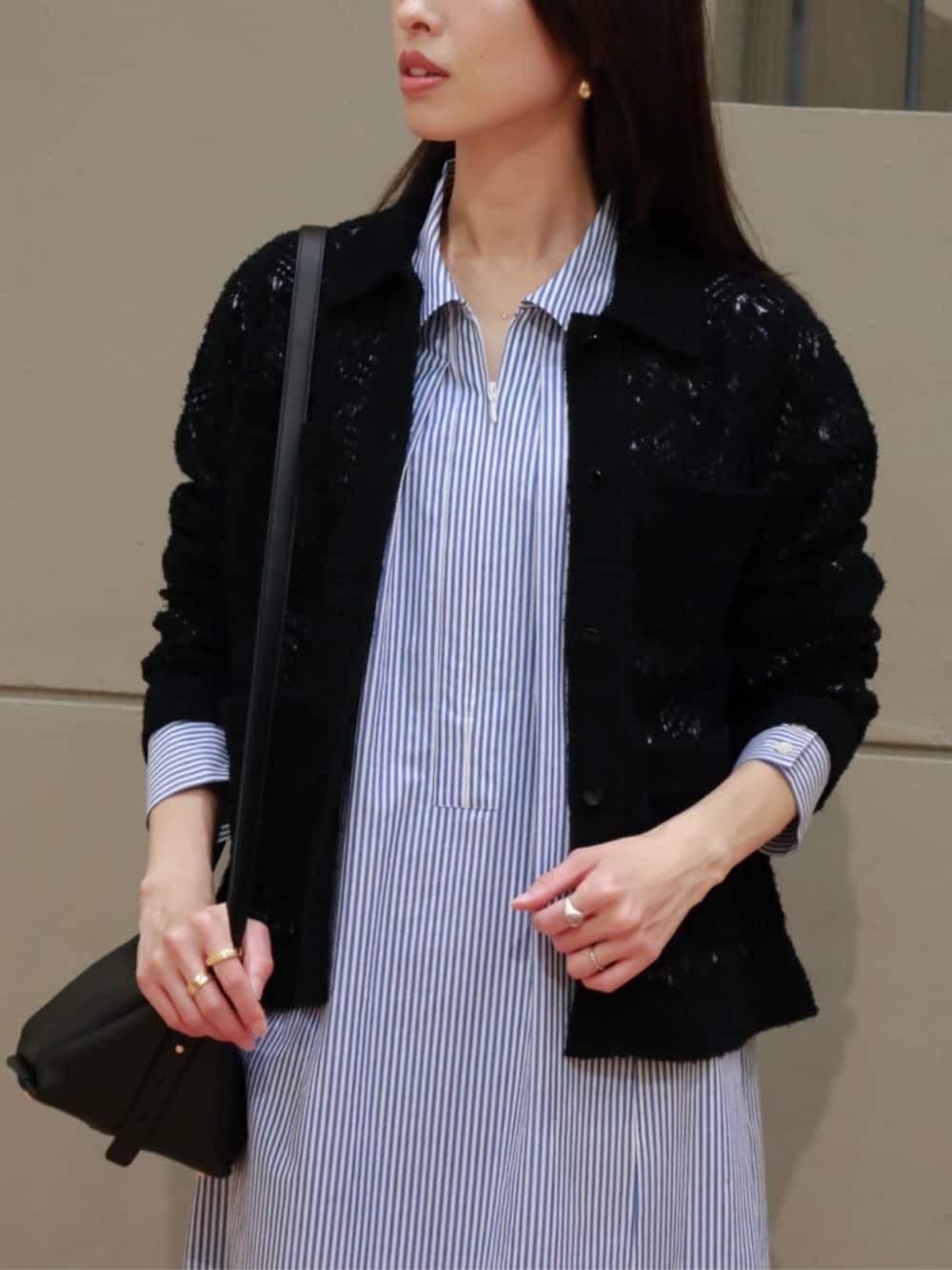 ブラック系のカーディガン/ボレロ、ブルー系のシャツワンピース、ブラック系のハンドバッグを着用したレディースの春コーディネートの2枚目の写真