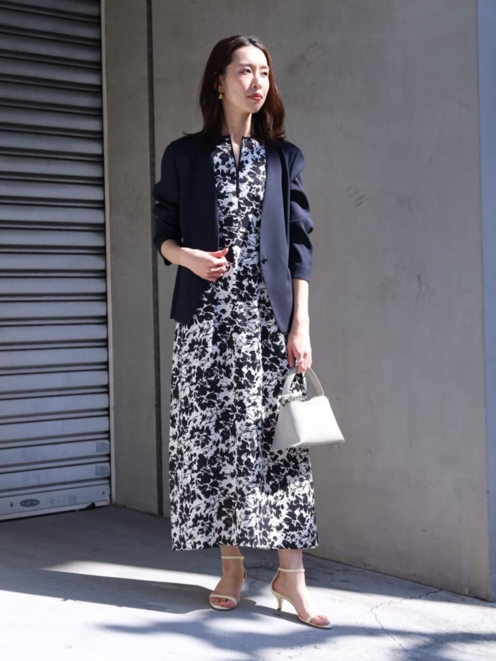 ブラック系のワンピース、ブルー系のノーカラージャケット、イエロー系のサンダルを着用したレディースの春コーディネートの2枚目の写真