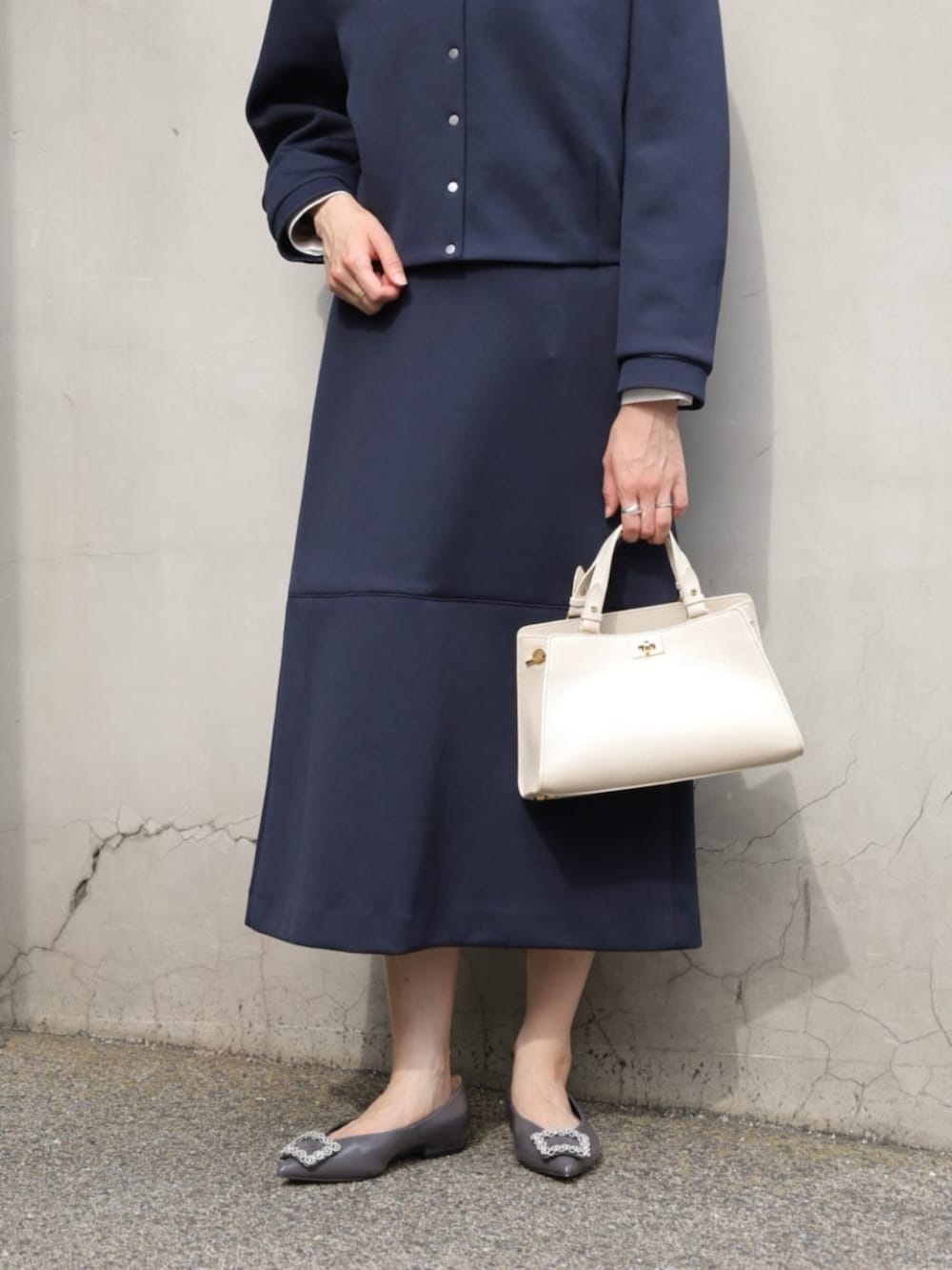 グレー系のパンプス、ブルー系のノーカラージャケット、ブルー系のスカートを着用したレディースの秋コーディネートの3枚目の写真