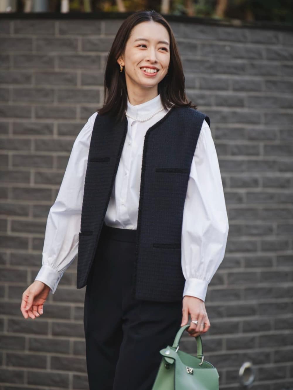 ブラック系のパンプス、ブルー系のベストを着用したレディースの冬コーディネートの2枚目の写真