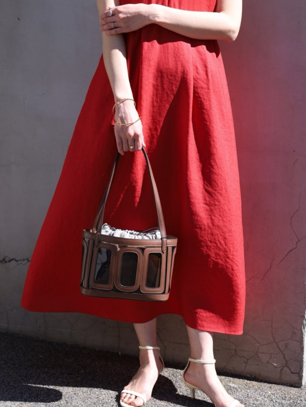 イエロー系のサンダル、レッド系のワンピース、ブラウン系のハンドバッグを着用したレディースの夏コーディネートの3枚目の写真