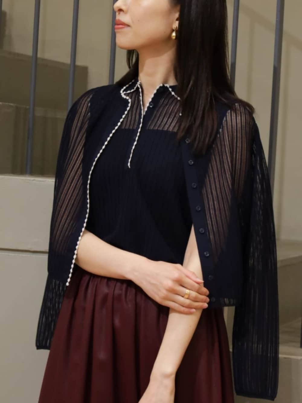 ブルー系のカーディガン/ボレロ、ブルー系のニット/セーター、レッド系のスカートを着用したレディースの夏コーディネートの2枚目の写真