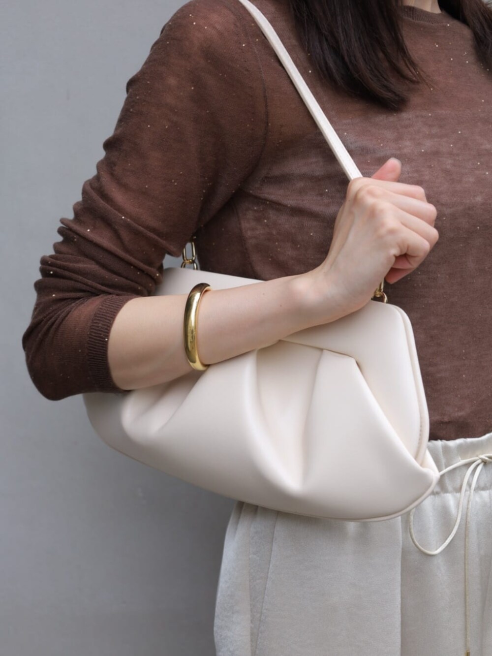 ベージュ系のその他アウター、グレー系のニット/セーター、ホワイト系のクラッチバッグを着用したレディースの秋コーディネートの5枚目の写真