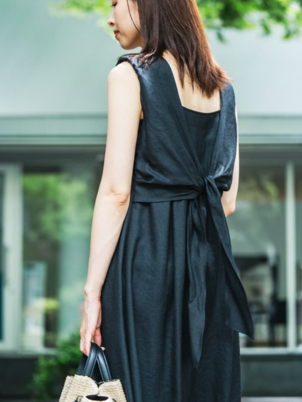 ブラック系のワンピース、ホワイト系のサンダル、ベージュ系のかごバッグを着用したレディースの夏コーディネートの2枚目の写真