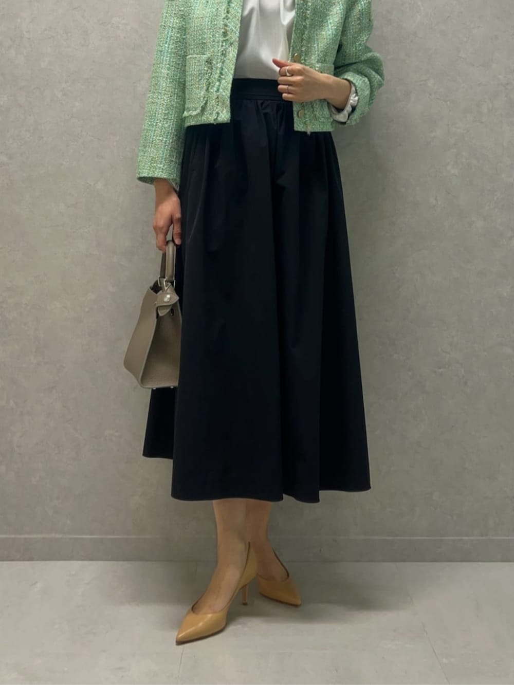 グリーン系のノーカラージャケット、ホワイト系のシャツ/ブラウス、ブルー系のスカートを着用したレディースの冬コーディネートの3枚目の写真