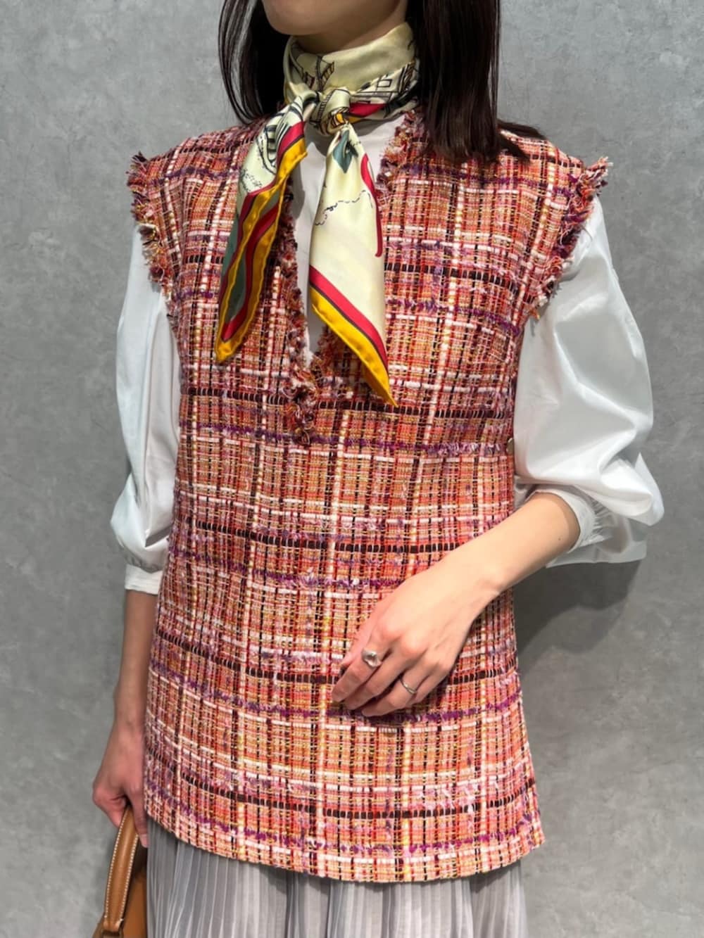 ベージュ系のスカート、ホワイト系のシャツ/ブラウス、ピンク系のベストを着用したレディースの春コーディネートの2枚目の写真