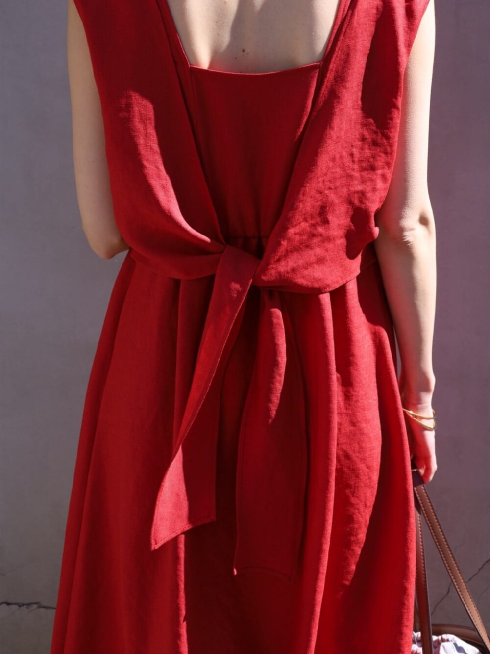 イエロー系のサンダル、レッド系のワンピース、ブラウン系のハンドバッグを着用したレディースの夏コーディネートの4枚目の写真