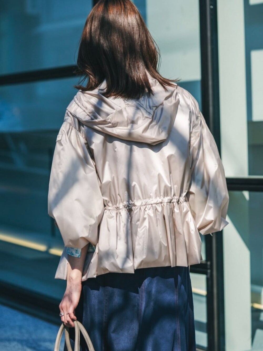 ベージュ系のその他アウター、ブルー系のベスト、ブルー系のデニムスカートを着用したレディースの春コーディネートの3枚目の写真