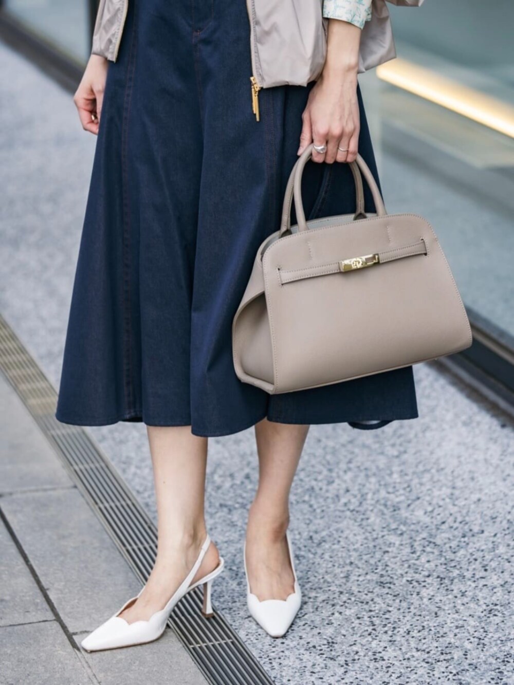 ベージュ系のその他アウター、ブルー系のベスト、ブルー系のデニムスカートを着用したレディースの春コーディネートの4枚目の写真