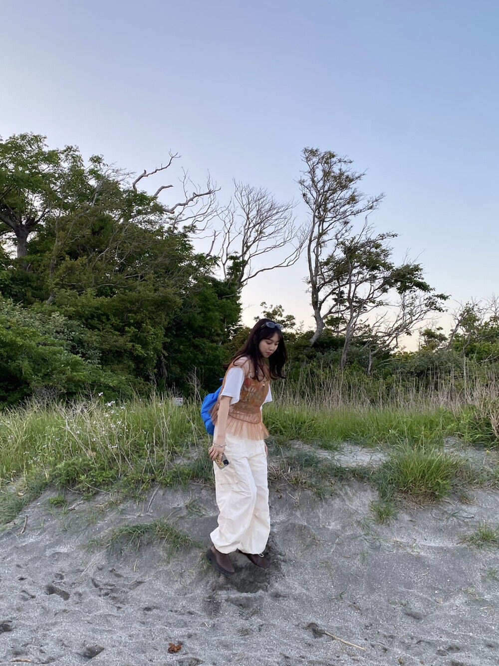 ホワイト系のカーゴパンツ、ブラウン系のTシャツ/カットソー、ブルー系のバックパック/リュックを着用したレディースの春コーディネートの2枚目の写真