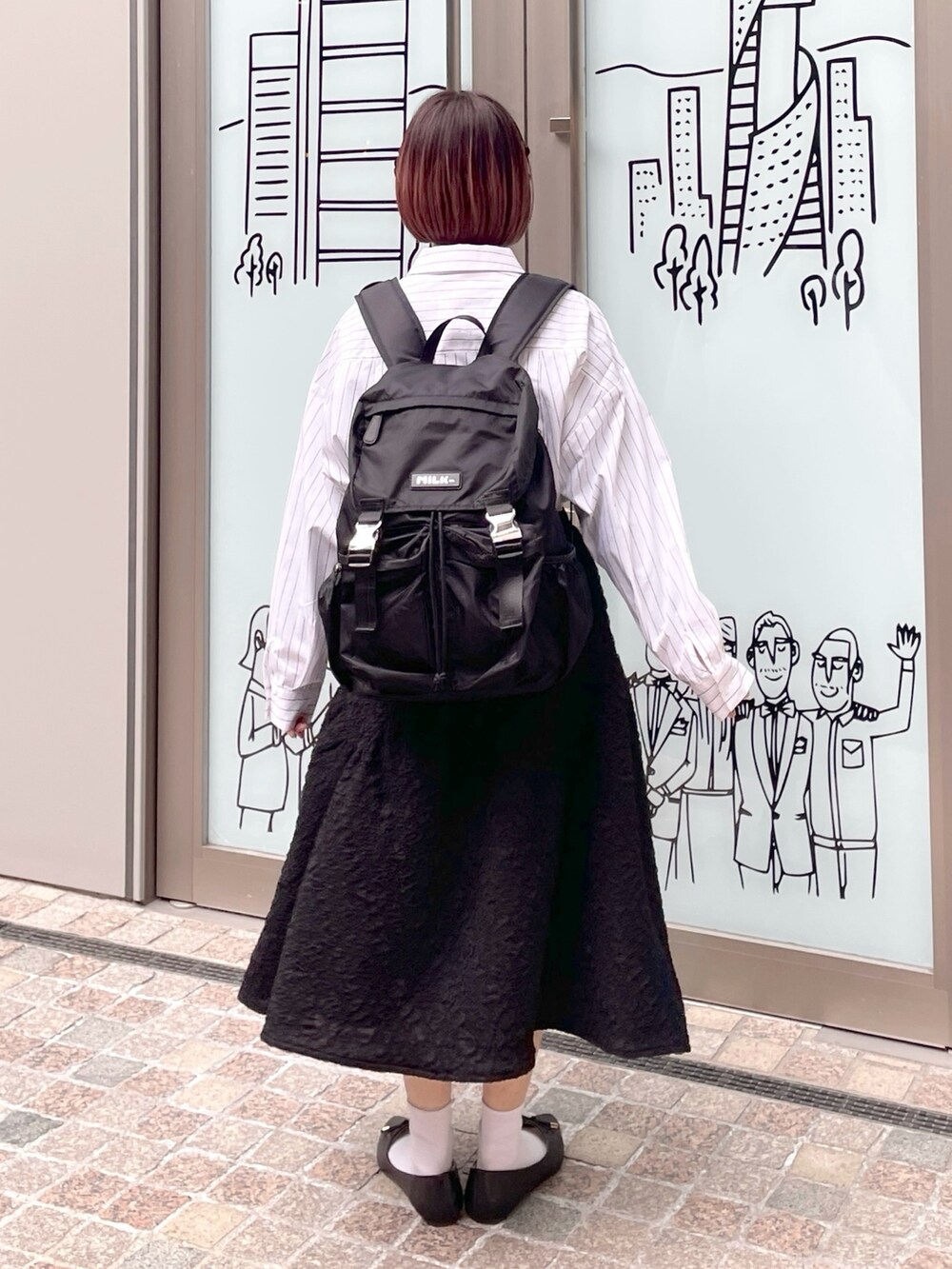 ホワイト系のシャツ/ブラウス、ブラック系のスカート、ブラック系のバックパック/リュックを着用したレディースの冬コーディネートの2枚目の写真