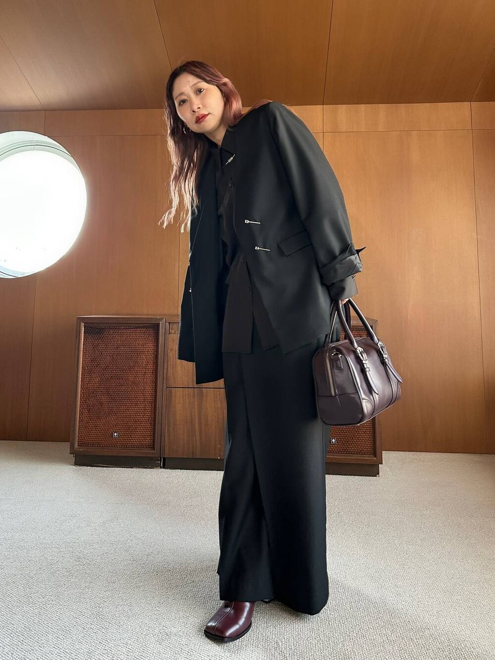 ブラウン系のボストンバッグ、レッド系のブーツを着用したレディースの秋コーディネートの5枚目の写真