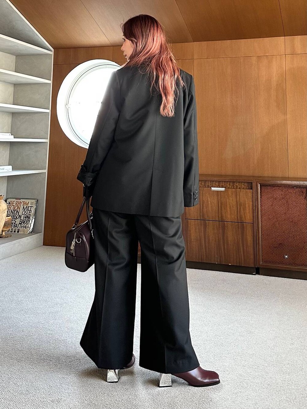 ブラウン系のボストンバッグ、レッド系のブーツを着用したレディースの秋コーディネートの2枚目の写真