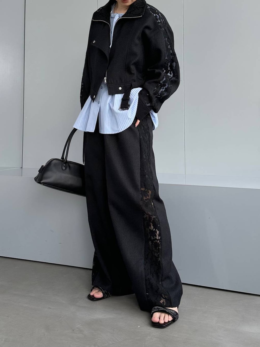 ブラック系のハンドバッグ、ブラック系のスラックス、ブラック系のブルゾンを着用したレディースの春コーディネートの8枚目の写真