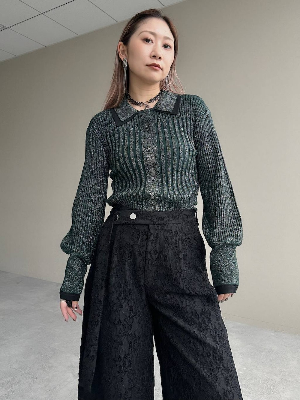 グレー系のブーツ、グリーン系のカーディガン/ボレロ、シルバー系のイヤリングを着用したレディースの秋コーディネートの3枚目の写真