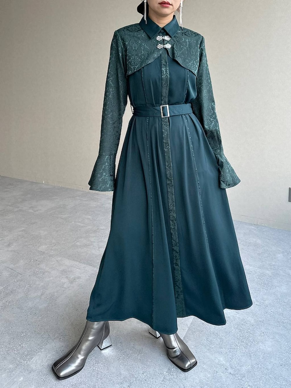 シルバー系のブーツ、グリーン系のワンピース、シルバー系のイヤリングを着用したレディースの秋コーディネートの5枚目の写真