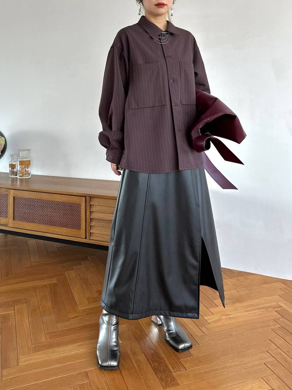 レッド系のトートバッグ、ブラック系のスカート、シルバー系のブーツを着用したレディースの夏コーディネートの7枚目の写真