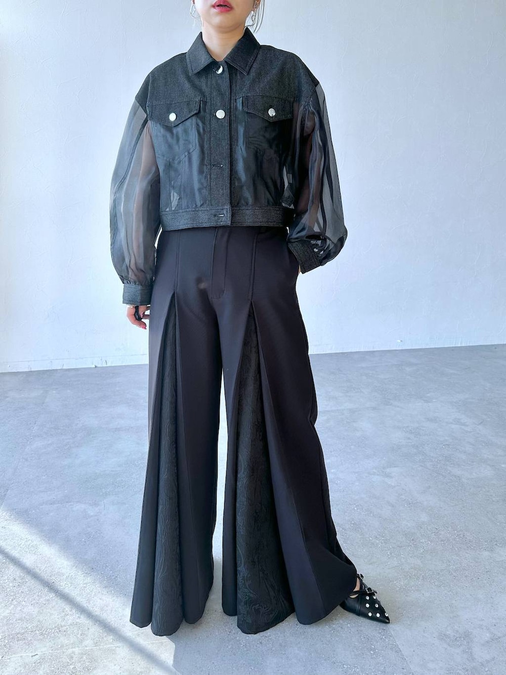 ブラック系のスラックス、ブラック系のパンプス、ブラック系のブルゾンを着用したレディースの夏コーディネートの6枚目の写真