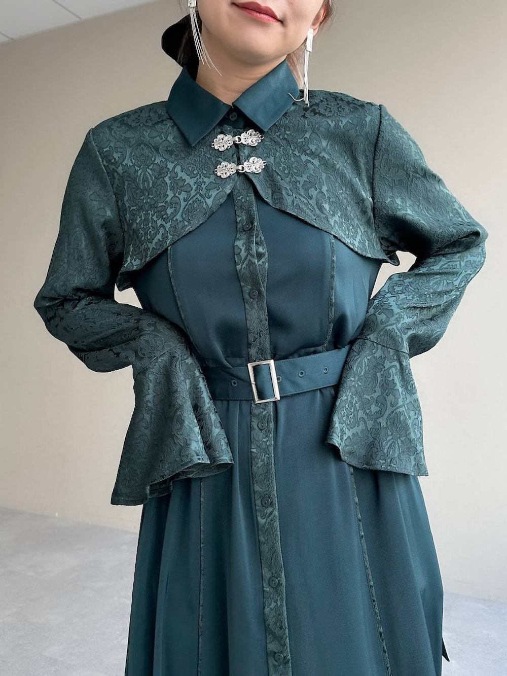 シルバー系のブーツ、グリーン系のワンピース、シルバー系のイヤリングを着用したレディースの秋コーディネートの6枚目の写真