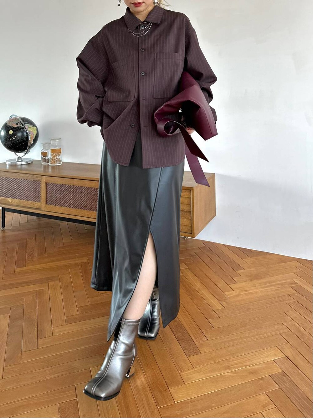 レッド系のトートバッグ、ブラック系のスカート、シルバー系のブーツを着用したレディースの夏コーディネートの6枚目の写真