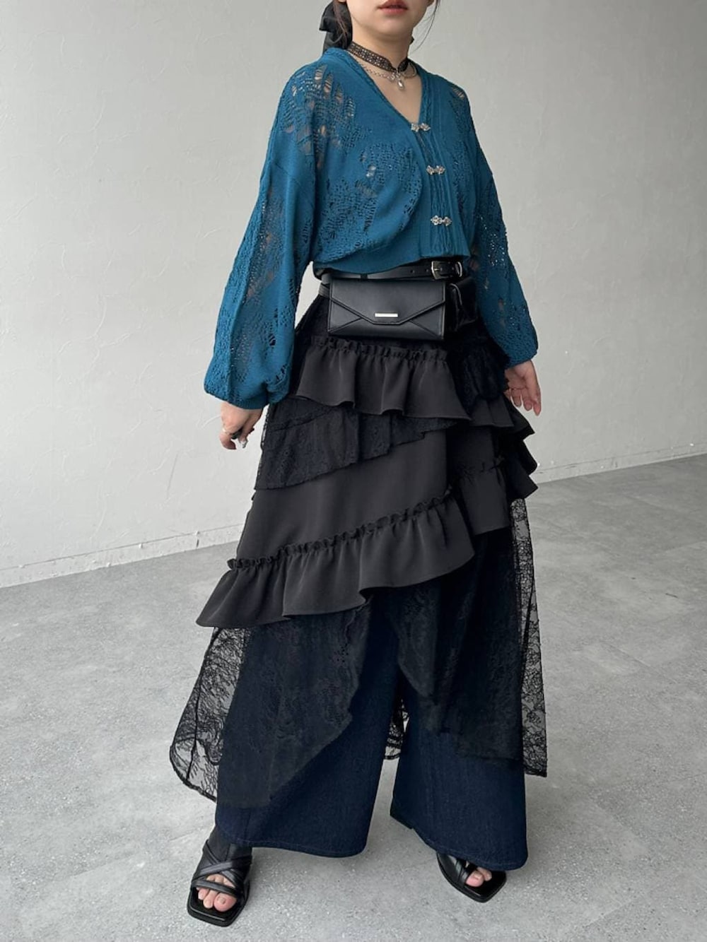 ブラック系のスカート、ブラック系のサンダル、ブルー系のデニムパンツを着用したレディースの春コーディネートの7枚目の写真