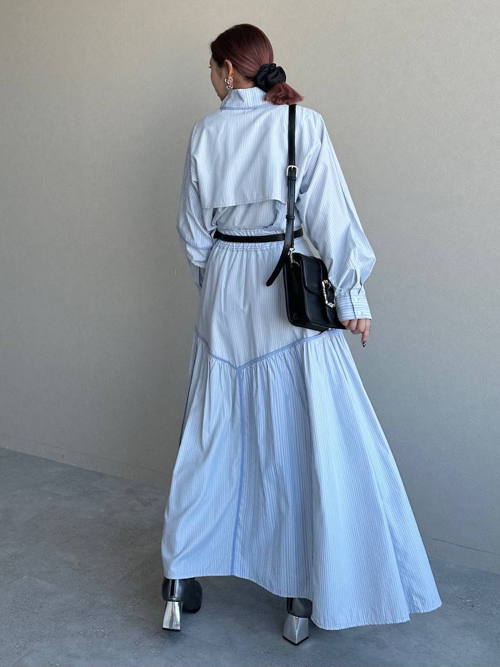 ブラック系のショルダーバッグ、シルバー系のブーツ、ブルー系のスカートを着用したレディースの冬コーディネートの2枚目の写真