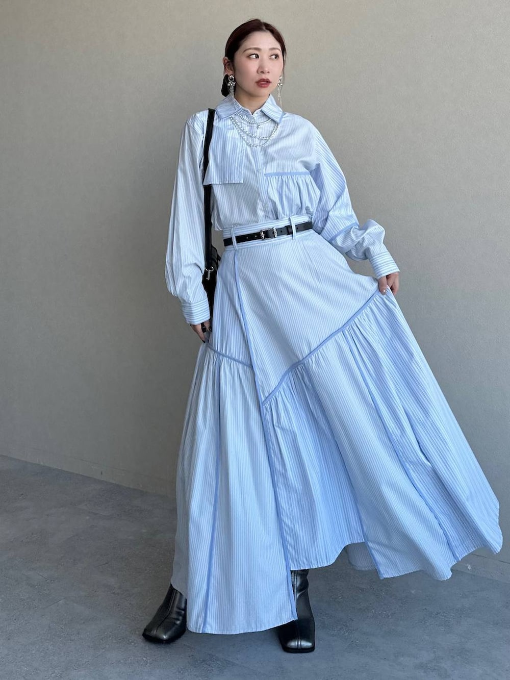 ブラック系のショルダーバッグ、シルバー系のブーツ、ブルー系のスカートを着用したレディースの冬コーディネートの3枚目の写真