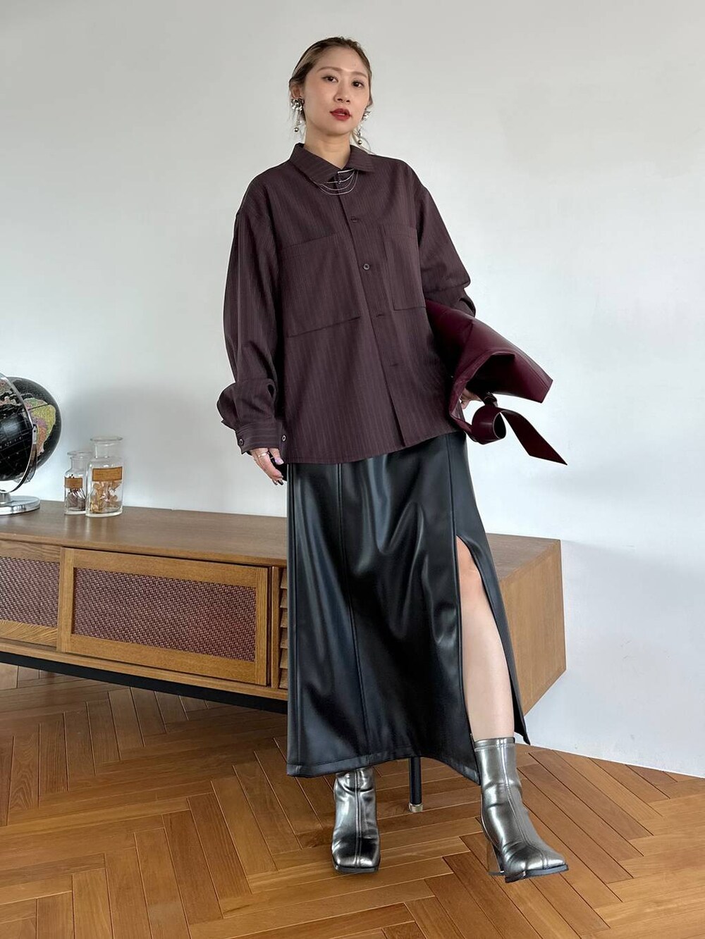 レッド系のトートバッグ、ブラック系のスカート、シルバー系のブーツを着用したレディースの夏コーディネートの9枚目の写真