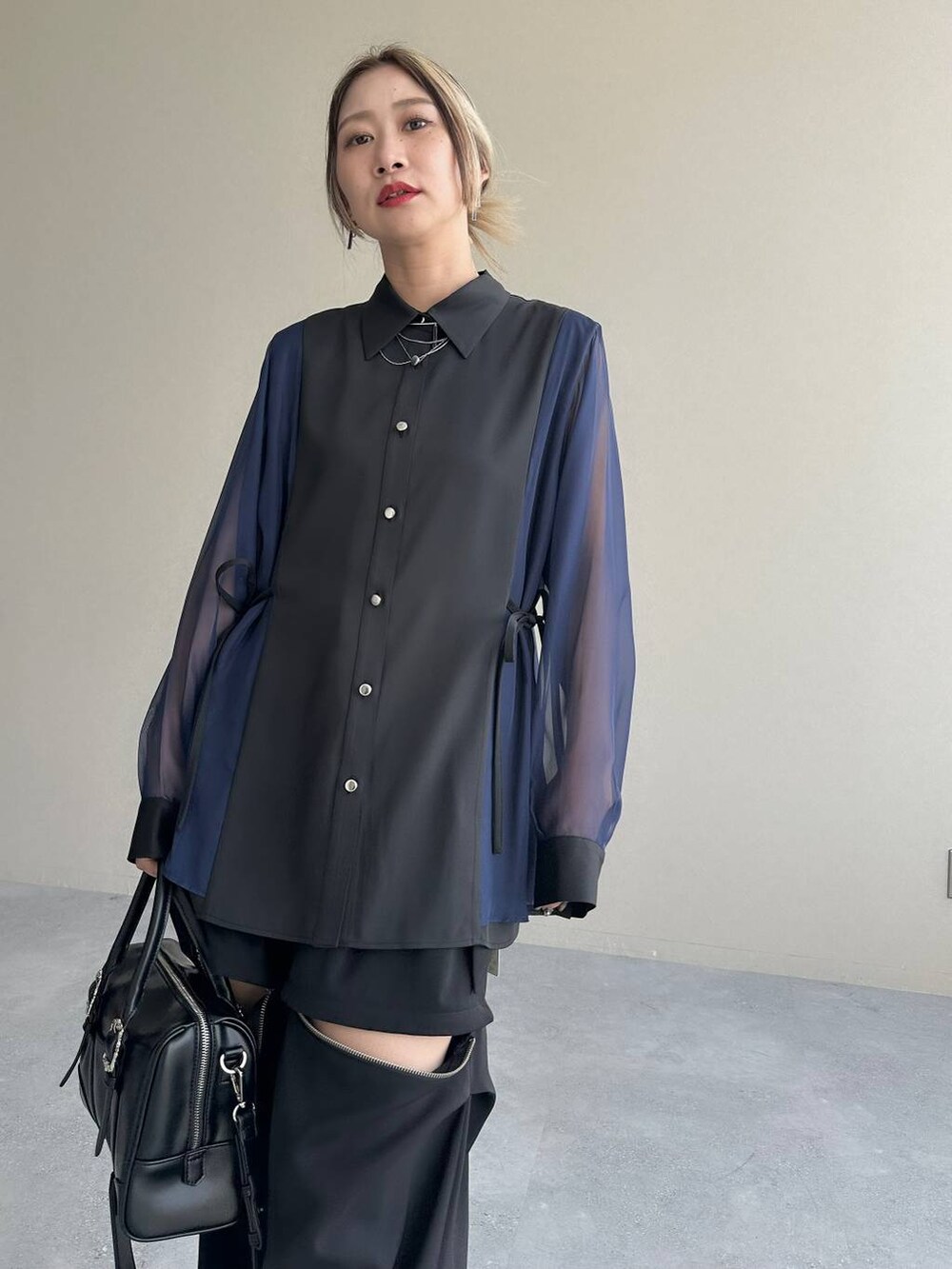 ブラック系のカーゴパンツ、ブラック系のボストンバッグ、シルバー系のブーツを着用したレディースの夏コーディネートの3枚目の写真