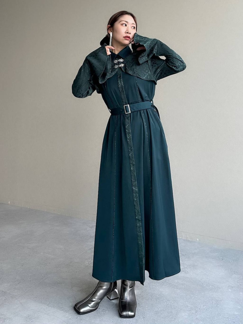 シルバー系のブーツ、グリーン系のワンピース、シルバー系のイヤリングを着用したレディースの秋コーディネートの8枚目の写真