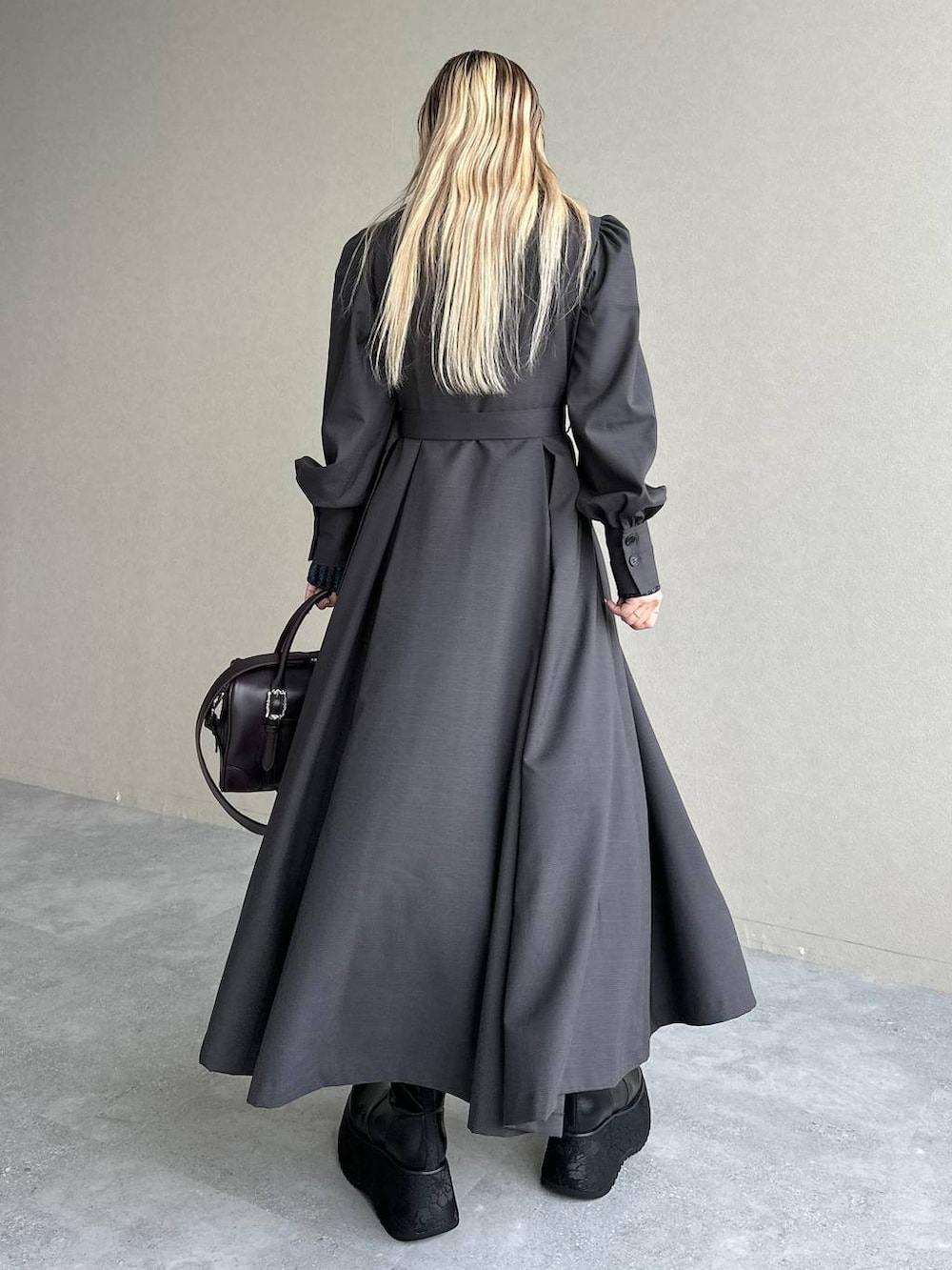 ブルー系のニット/セーター、ブラウン系のボストンバッグ、グレー系のワンピースを着用したレディースの秋コーディネートの2枚目の写真