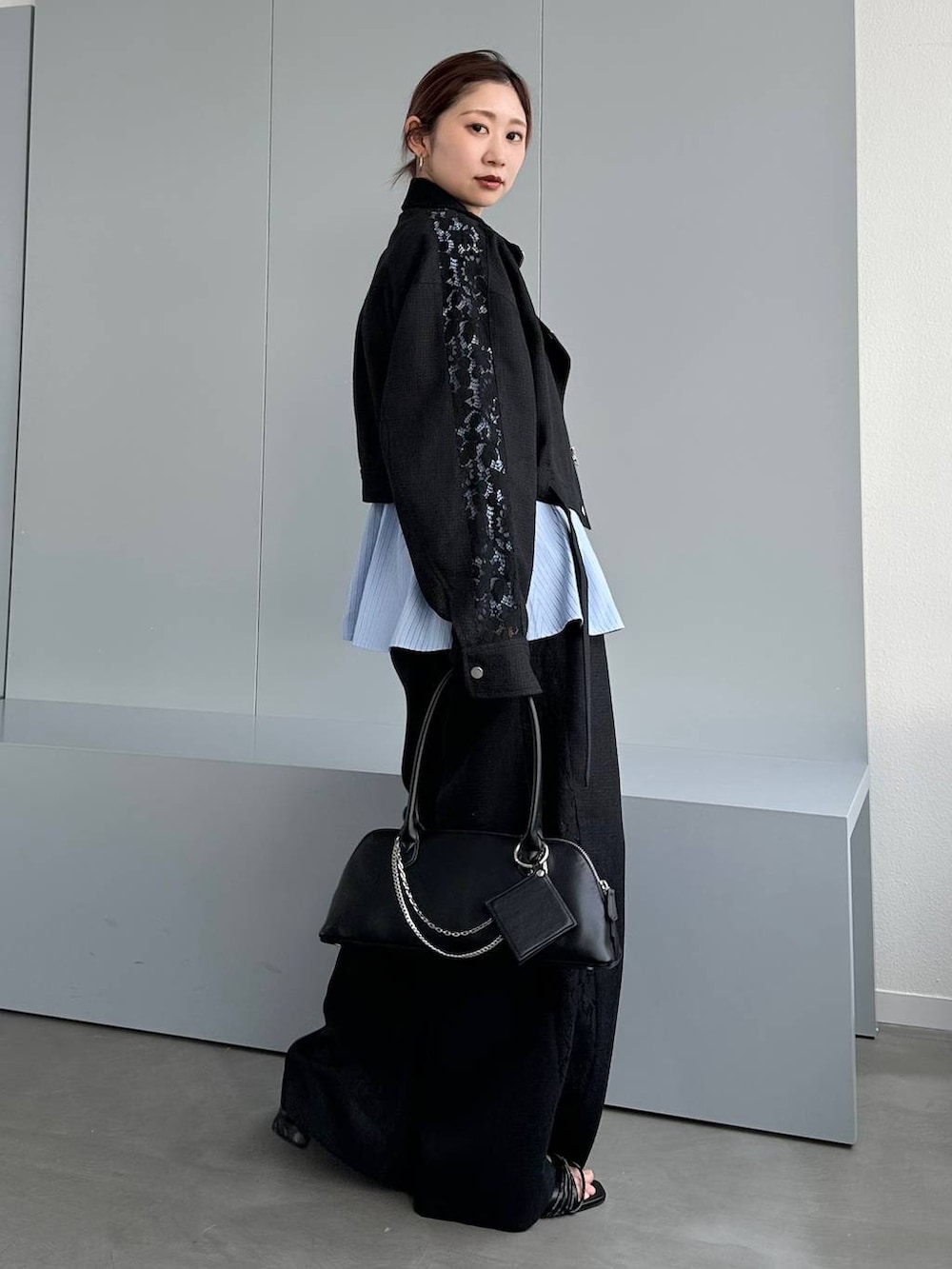 ブラック系のハンドバッグ、ブラック系のスラックス、ブラック系のブルゾンを着用したレディースの春コーディネートの3枚目の写真